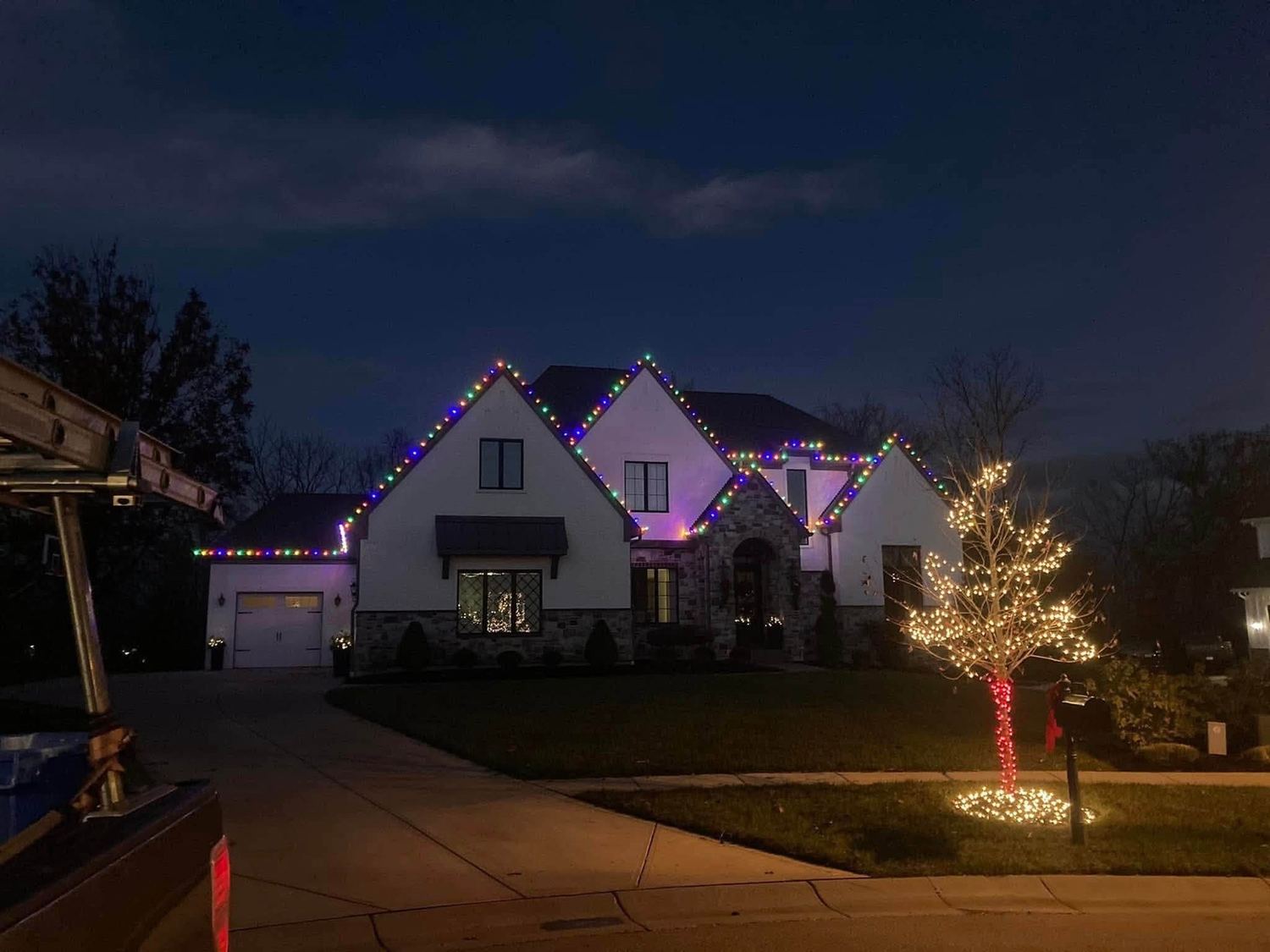 Multicolor roofline with a wrapped tree out front &mdash; Christmas light installation in Greater Cincinnati by Mike&rsquo;s Cincinnati Christmas Lights